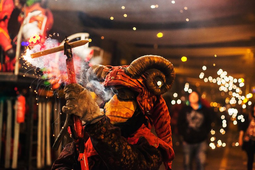 Imagen de una persona caracterizada de demonio sosteniendo un fuego artificial