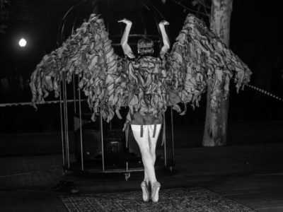 Imagen en blanco y negro de una persona bailando de espaldas con una vestimenta de pájaro