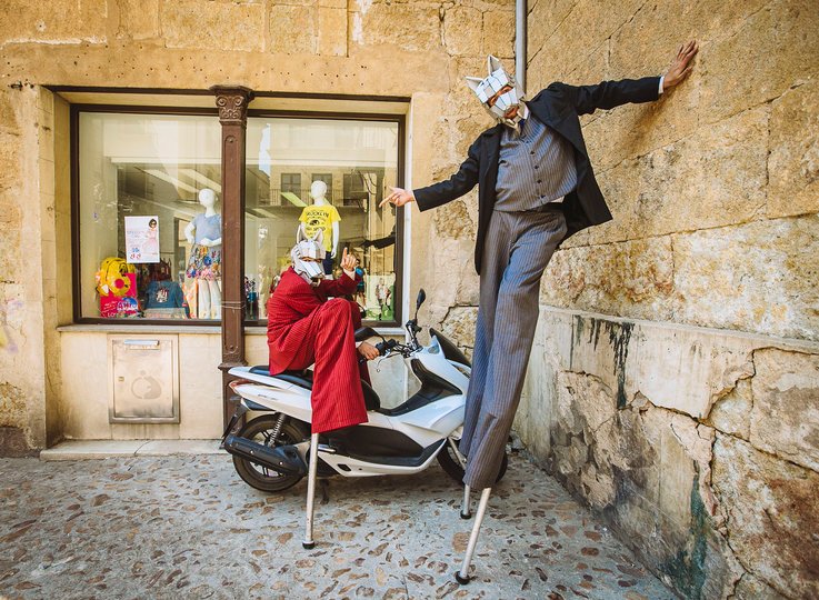 Imagen de dos personas vestidas de traje de colores con máscaras de lobo posando, una de ellas encima de una moto