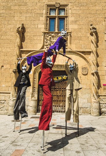Imagen de 4 personas vestidas con trajes de colores y con máscaras de lobos, una de ellas sosteniendo a otra
