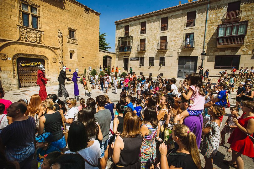 Imagen de 4 personas vestidas con trajes de colores y con máscaras de lobos en frente de mucho público