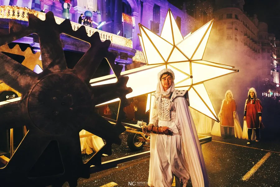 Imagen de una persona acompañando una carroza muy iluminada